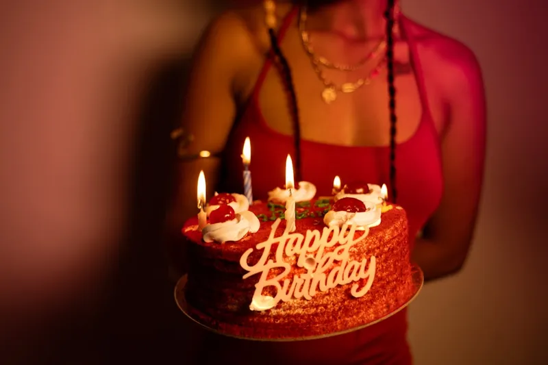 A woman holding a birthday cake with lit candles